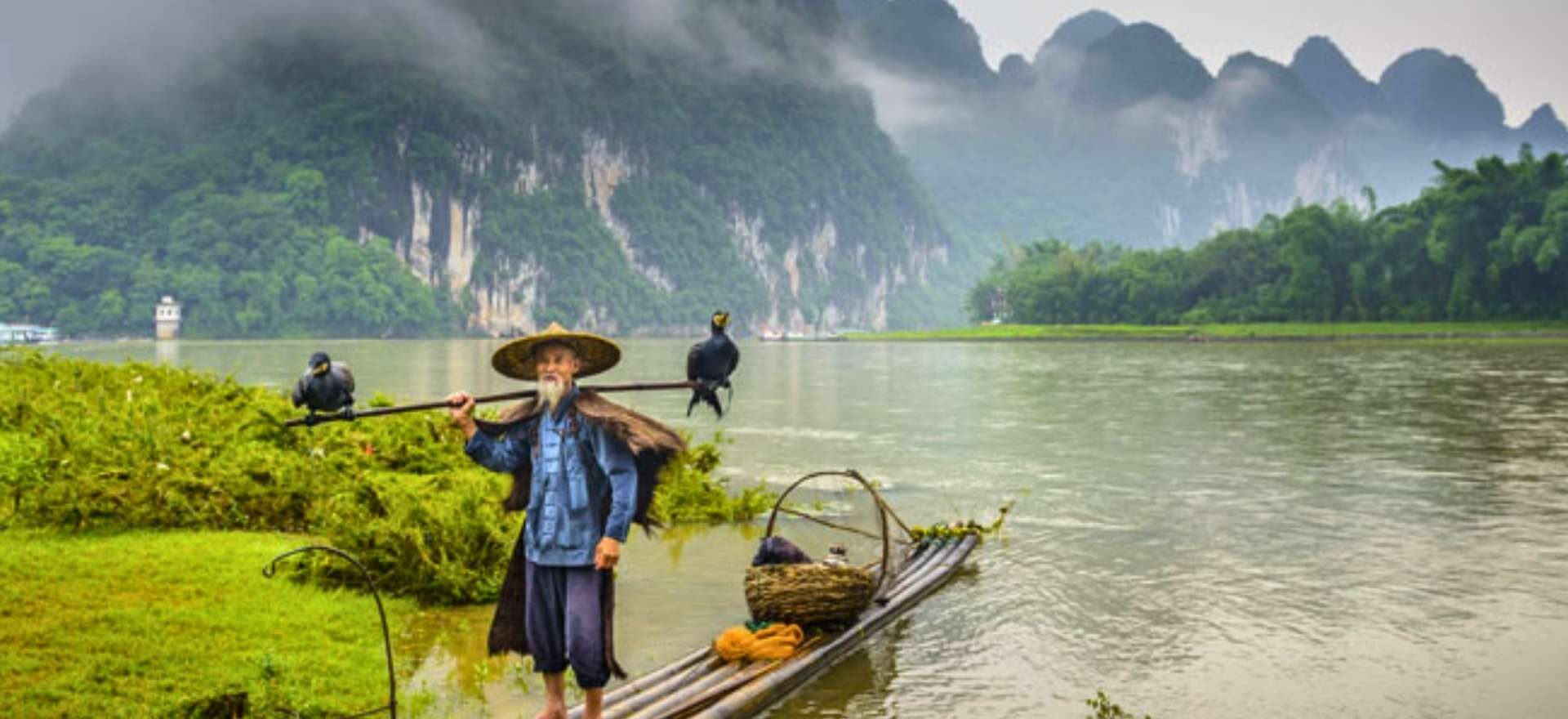Pescador tradicional chino con cormoranes en una balsa en el río Li, durante la excursión a Guilin y Yangshuo del circuito China con Panda de Traveland.