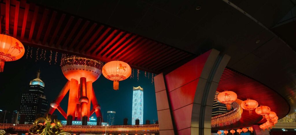 Farolillos rojos tradicionales iluminados frente a la Torre de la Perla Oriental en Shanghái, durante el circuito China con Panda de Traveland