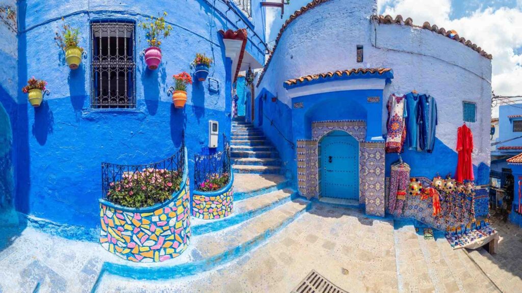 Callejón típico pintado de azul con escaleras y macetas floridas en la medina de Chauen, Marruecos.