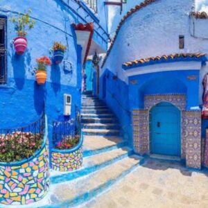 Callejón típico pintado de azul con escaleras y macetas floridas en la medina de Chauen, Marruecos.
