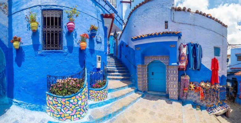 Callejón típico pintado de azul con escaleras y macetas floridas en la medina de Chauen, Marruecos.