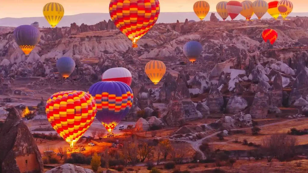 Viaje de Traveland: Globos aerostáticos volando sobre el paisaje rocoso de Capadocia en Turquía al amanecer