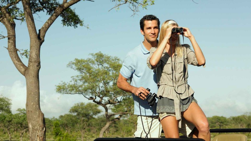 Pareja en un vehículo de safari observando la fauna en Kenia, viaje de novios aventurero.