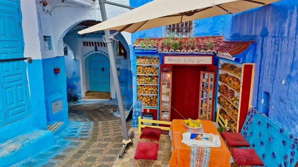 Norte de marruecos del rif. Pintoresco callejon azul con puesto de zumo de naranja y terraza pintada de colores en la medina de Chefchaouen Marruecos con Traveland