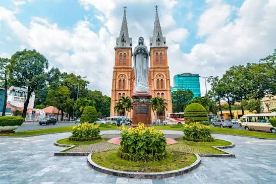 Estatua de la Virgen Maria frente a la fachada de ladrillo rojo de la Catedral Notre Dame en Ho Chi Minh Vietnam con Traveland