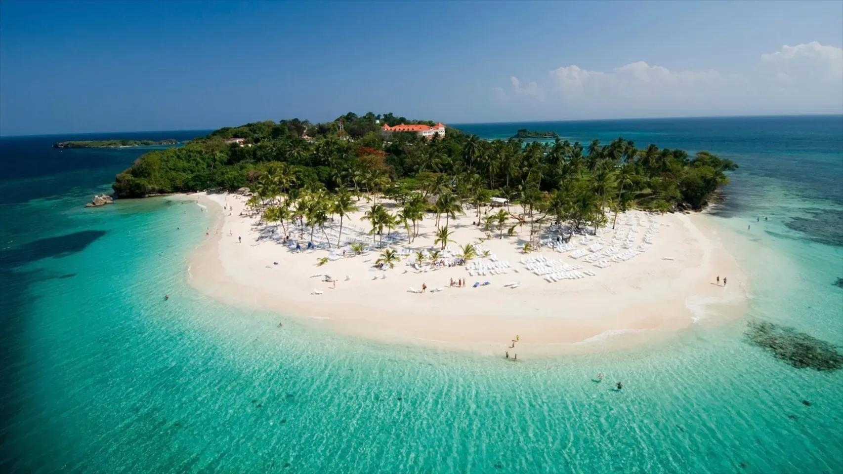 Vista aérea panorámica de la isla Cayo Levantado en Samaná, con su icónica playa de arena blanca, vegetación de palmeras tropicales y aguas turquesas transparentes
