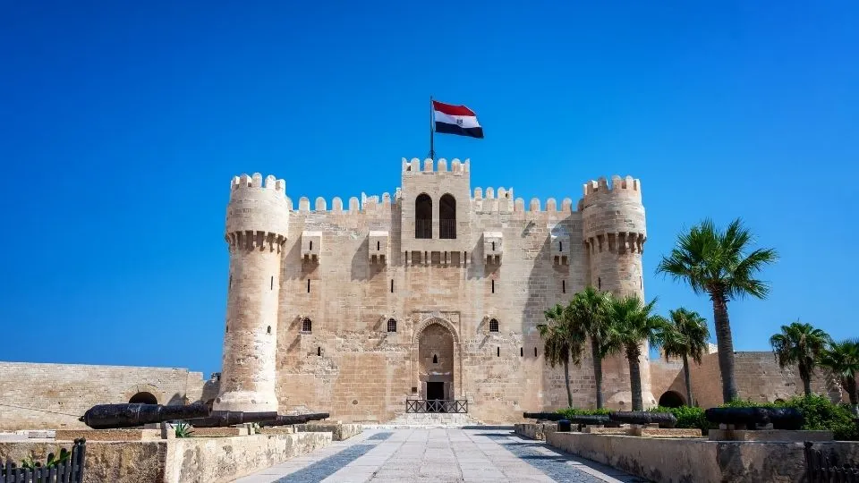 Fachada de la fortaleza historica de la Ciudadela de Qaitbay con cañones y bandera egipcia en Alejandria Egipto con Traveland