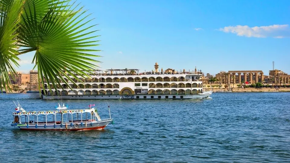 Barco de crucero y barca tradicional navegando por el rio Nilo con el Templo de Luxor al fondo en Egipto con Traveland