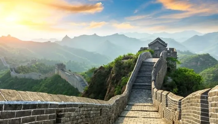 Vista panorámica de la Gran Muralla China serpenteando entre montañas al atardecer con Traveland