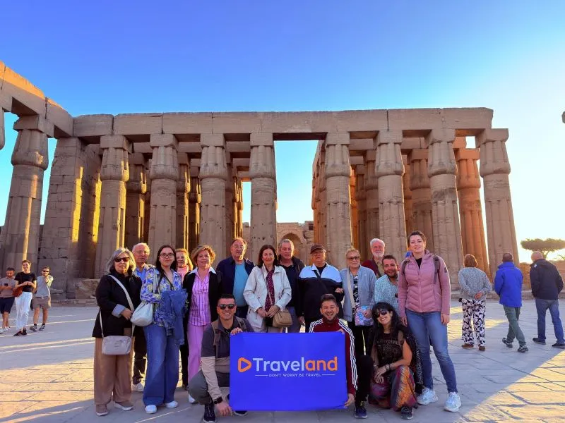 Agencia de Viajes en Alcalá de Guadaíra. Grupo de viajeros sonrientes sosteniendo la pancarta de Traveland en el patio de columnas del Templo de Luxor Egipto