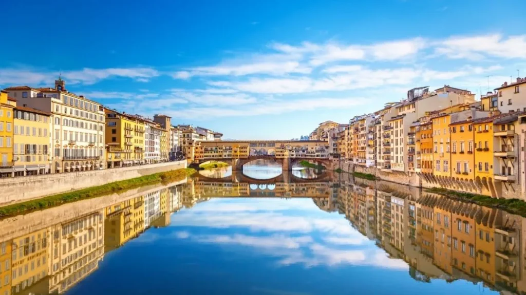 Panoramica del Ponte Vecchio con edificios coloridos reflejados en el rio Arno en Florencia Italia con Traveland