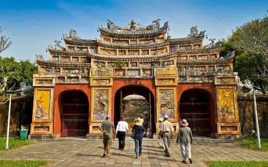 Turistas cruzando la colorida puerta ornamental Hien Nhon en la Ciudad Imperial de Hue Vietnam con Traveland