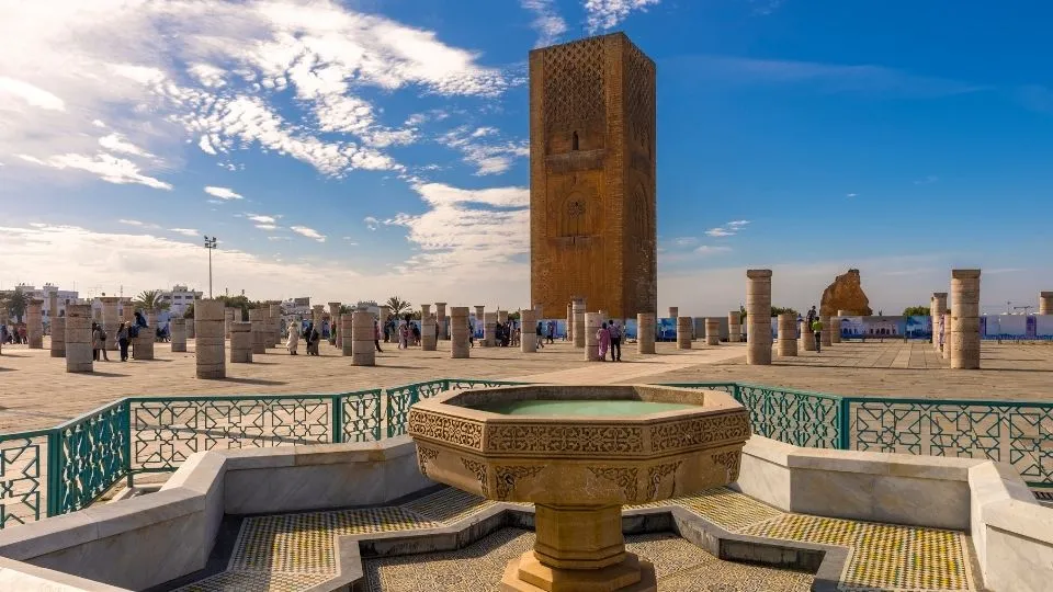 Fuente de piedra en primer plano y la historica Torre Hassan rodeada de columnas en Rabat Marruecos con Traveland
